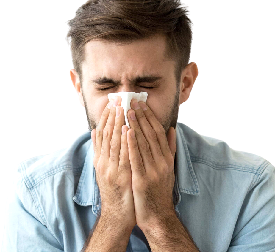 A man in a light blue shirt holding a tissue up to his nose with both hands and sneezing into it